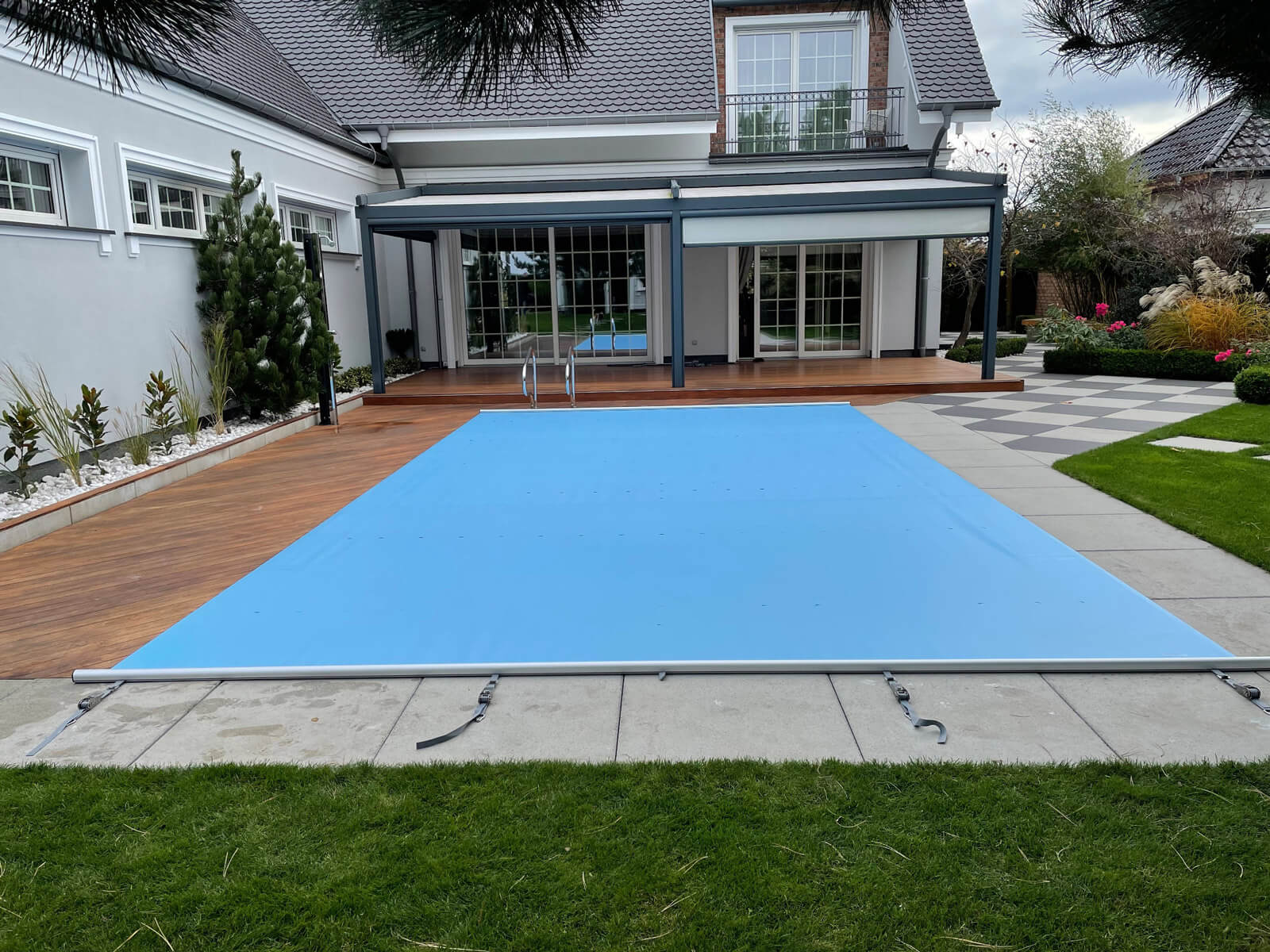 Blaue ExtraTop Sicherheitsabdeckung auf einem rechteckigen Pool vor einer Terrasse